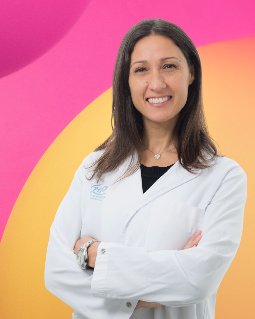 A smiling image of Laura Soucek in a lab coat against a branded Worldwide Cancer Research backdrop in yellow and pink